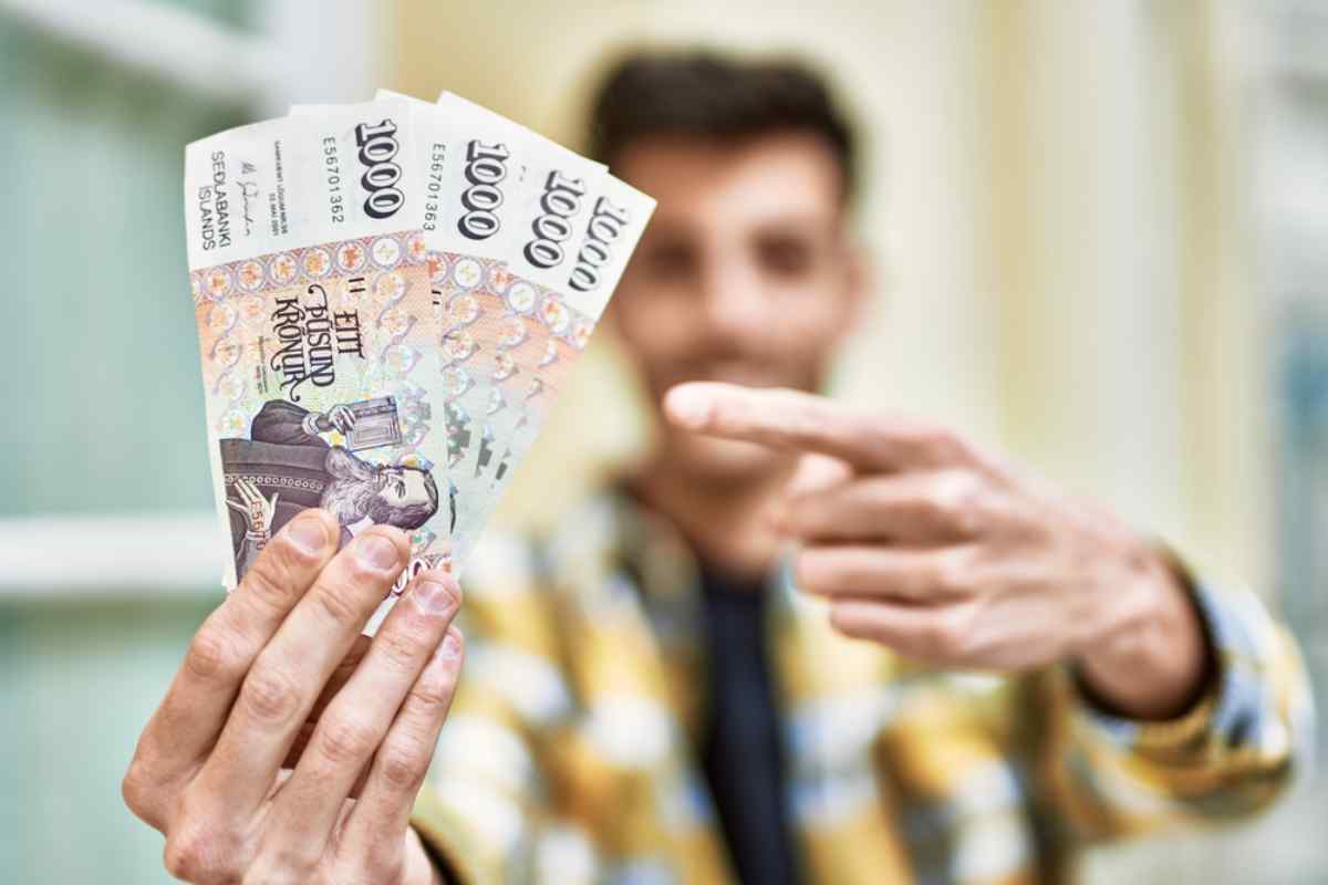 A person in an out-of-focus shot holding Icelandic krona banknotes.