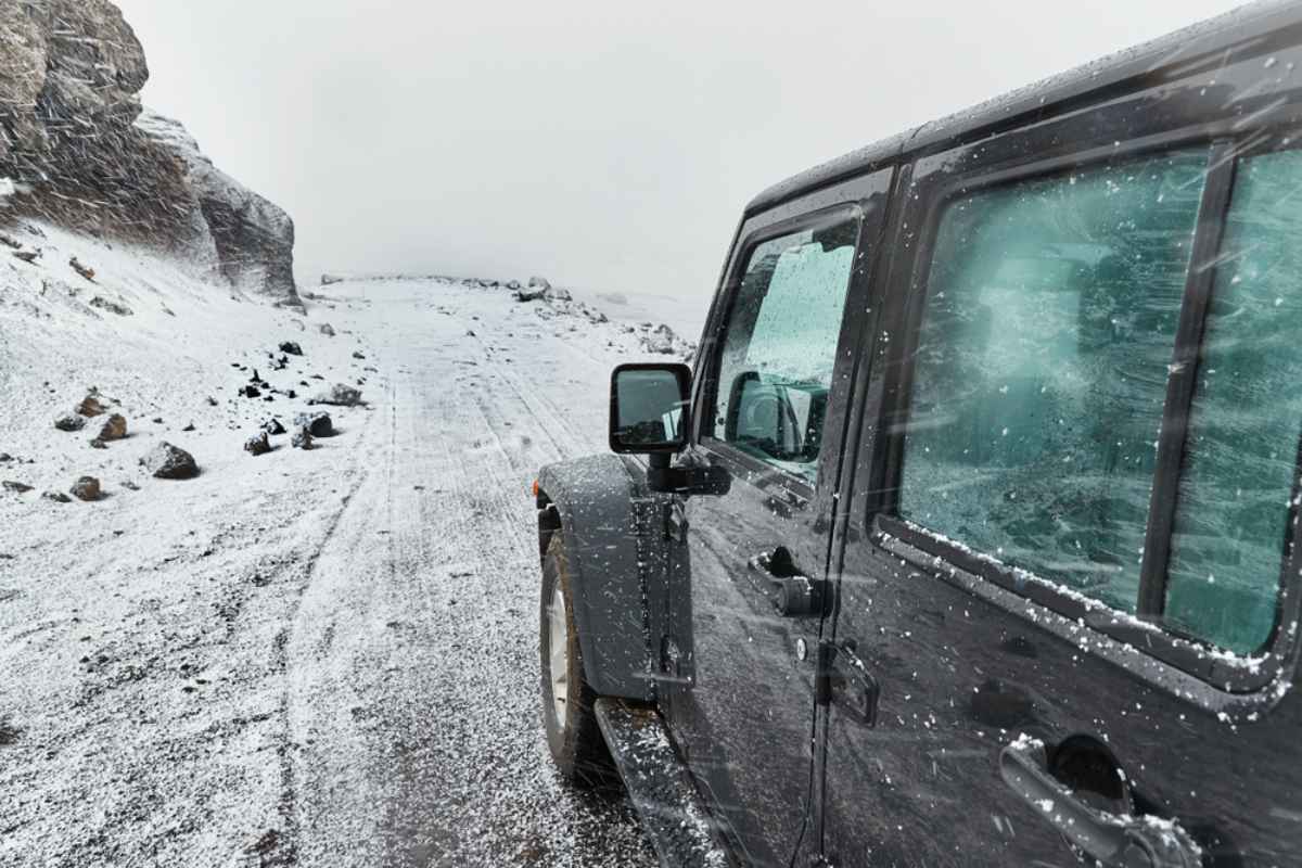 Driving a 4x4 in wintry Iceland A black 4x4 parked on a snow covered mountain road during strong wind and blowing snow in Iceland.