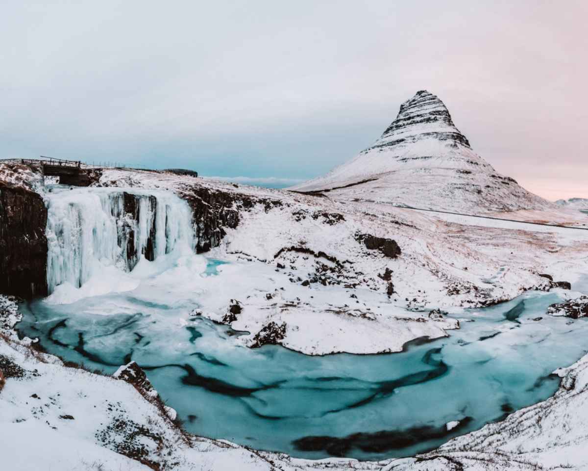 Snæfellsnes peninsula in Iceland Kirkjufell mountain and its frozen waterfall surrounded by snow and ice under soft winter light in Iceland.