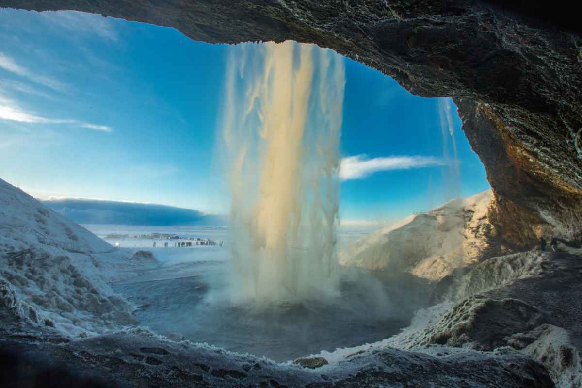 Seljalandsfoss's waterfall Seljalandsfoss waterfall seen from behind, with icy cliffs and a golden winter sunrise lighting the spray.