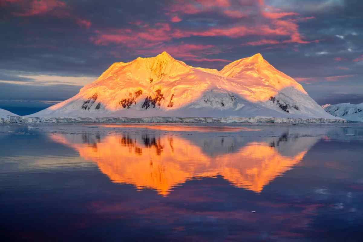 midnight sun reflecting on a snow covered mountain