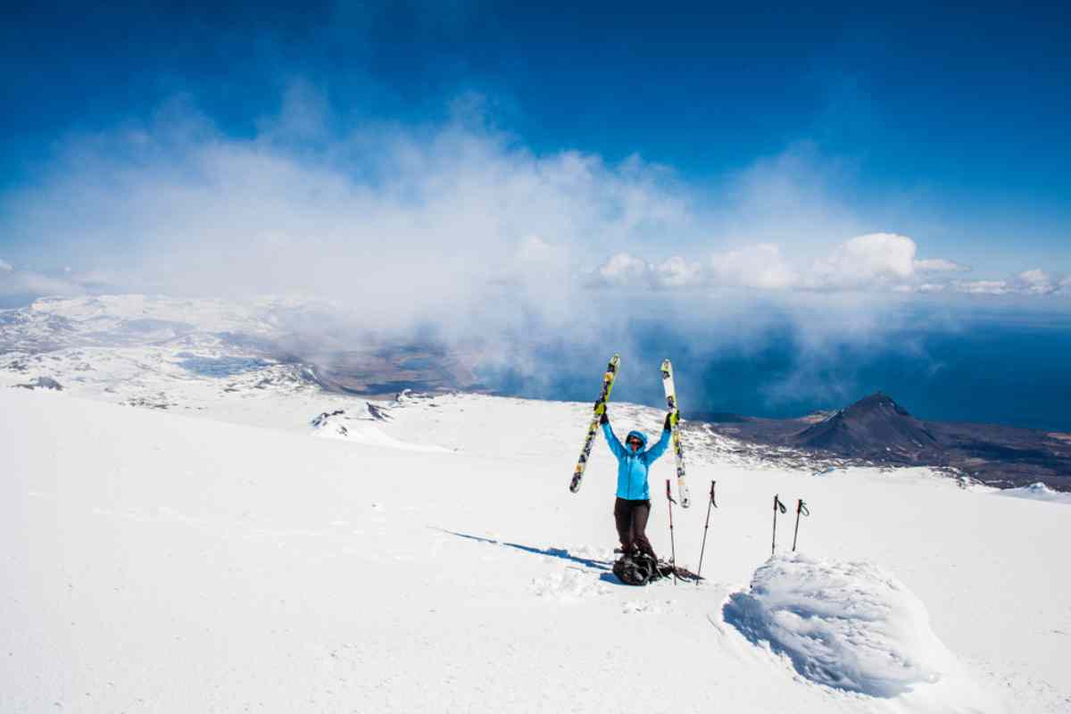 Skier holding her skis with ocean views