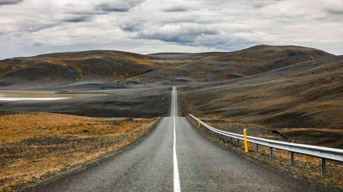General view of a winding Icelandic road away from urban centers on a cloudy day.