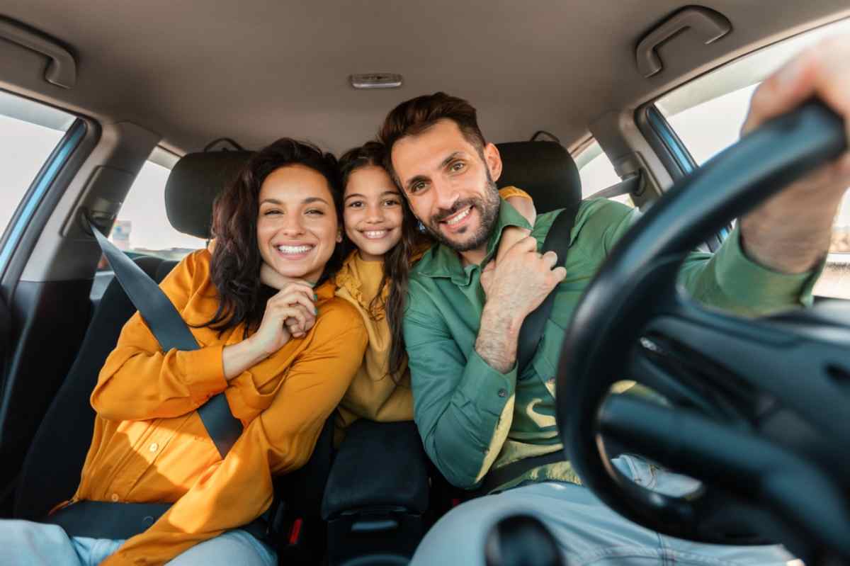 A woman, a man and a little girl look on smiling as they remain inside the vehicle.
