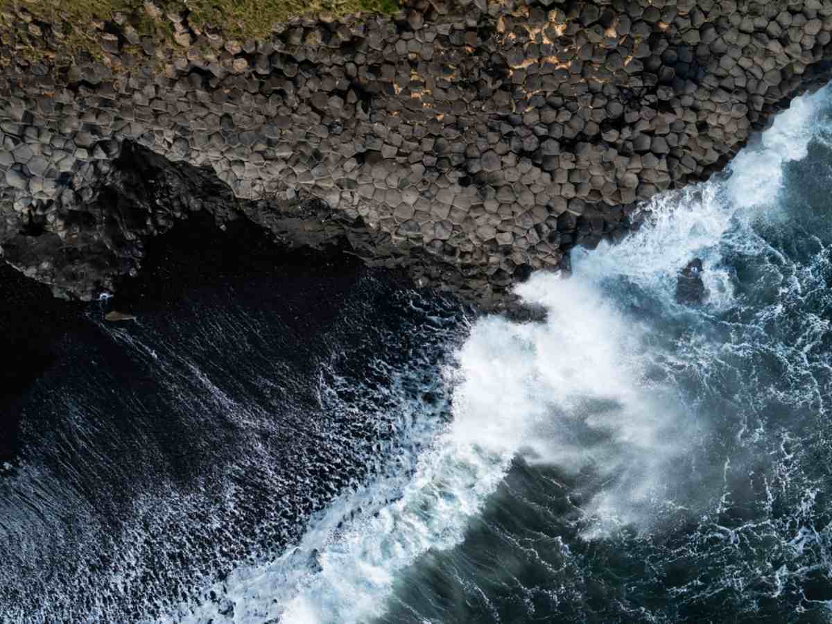 Aerial view of the waves at Reynisfjara beach as they break against the basalt columns and black sand