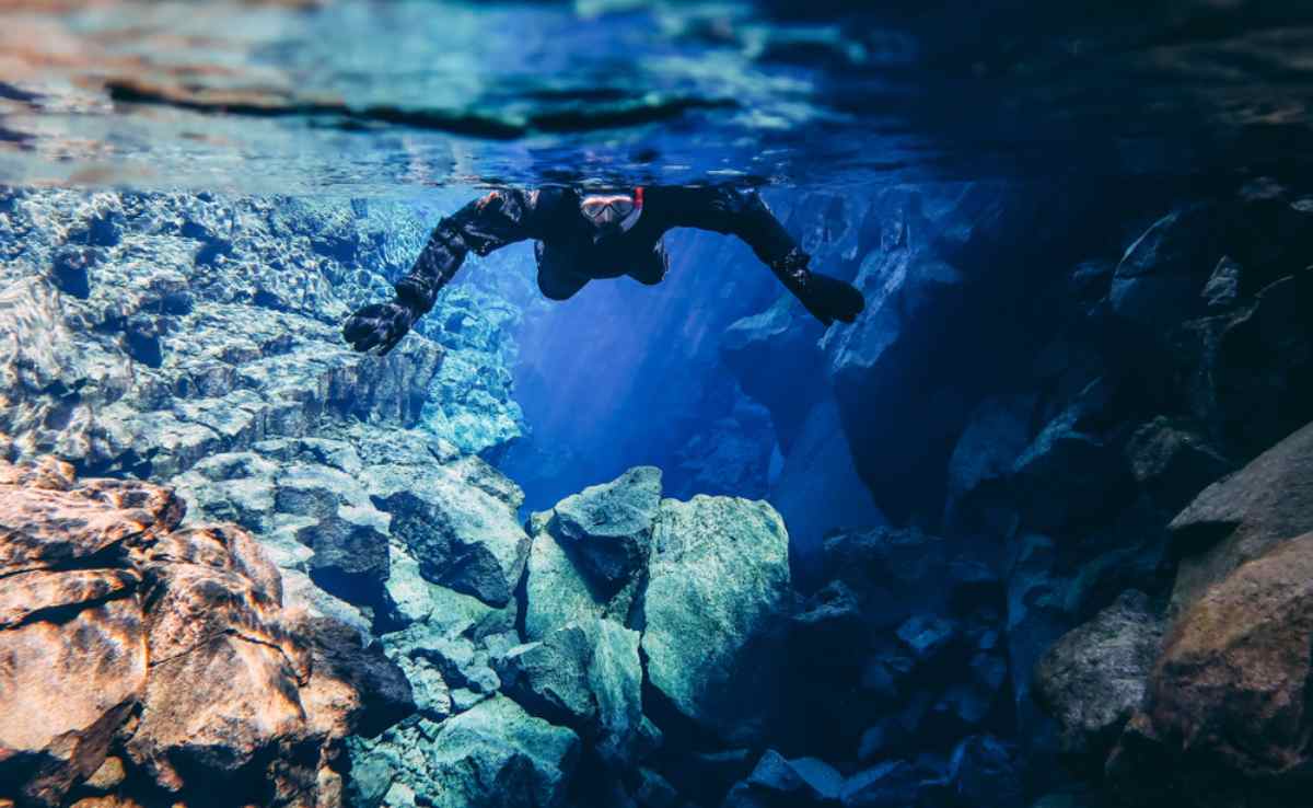 A person snorkels from inside the Silfra fissure in Iceland. 