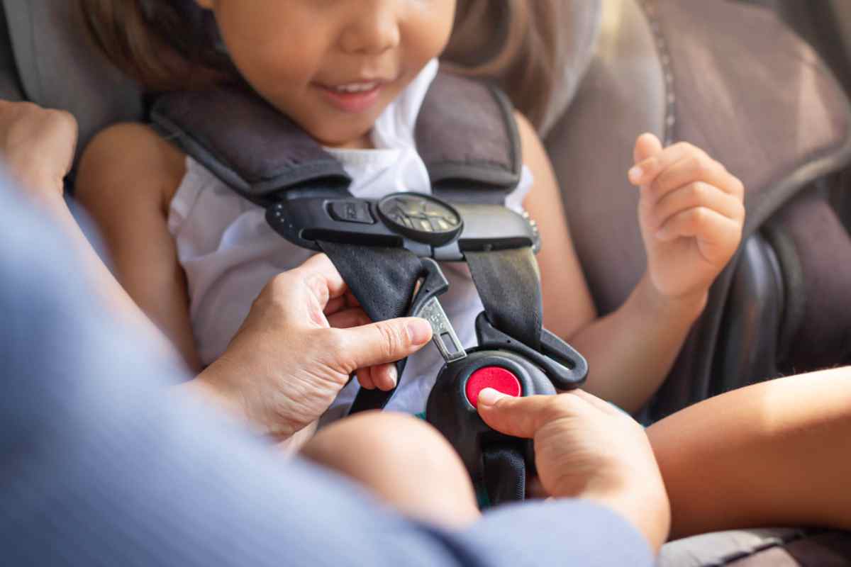 Frequently asked questions about the safety of children sitting in car seats An adult ensures that the safety mechanism of a child's car seat is securely locked.