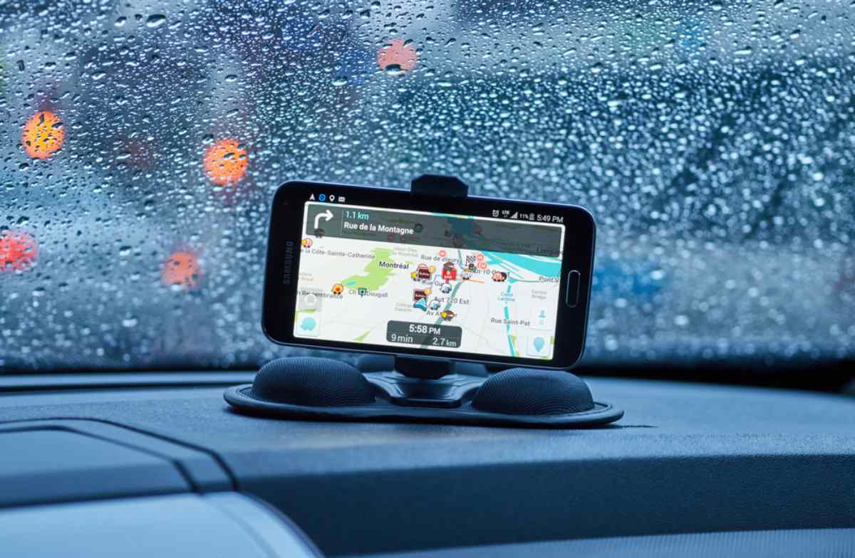 A GPS-enabled cell phone remains securely attached to the dashboard of a car as it drives through a downpour.