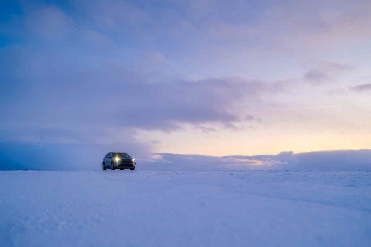 A vehicle remains parked on what looks like a cold winter morning in a completely snowy Icelandic area.