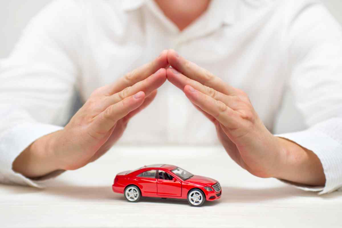 A person clasps his hands together to create a sort of roof over a miniature car.