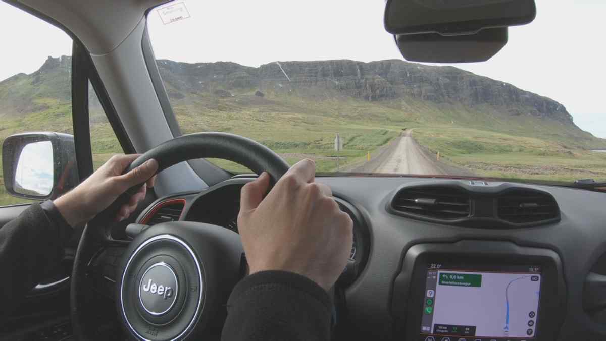 Point of view of a person driving a 4x4 on an Icelandic road, as the Jeep brand can be seen on the steering wheel.