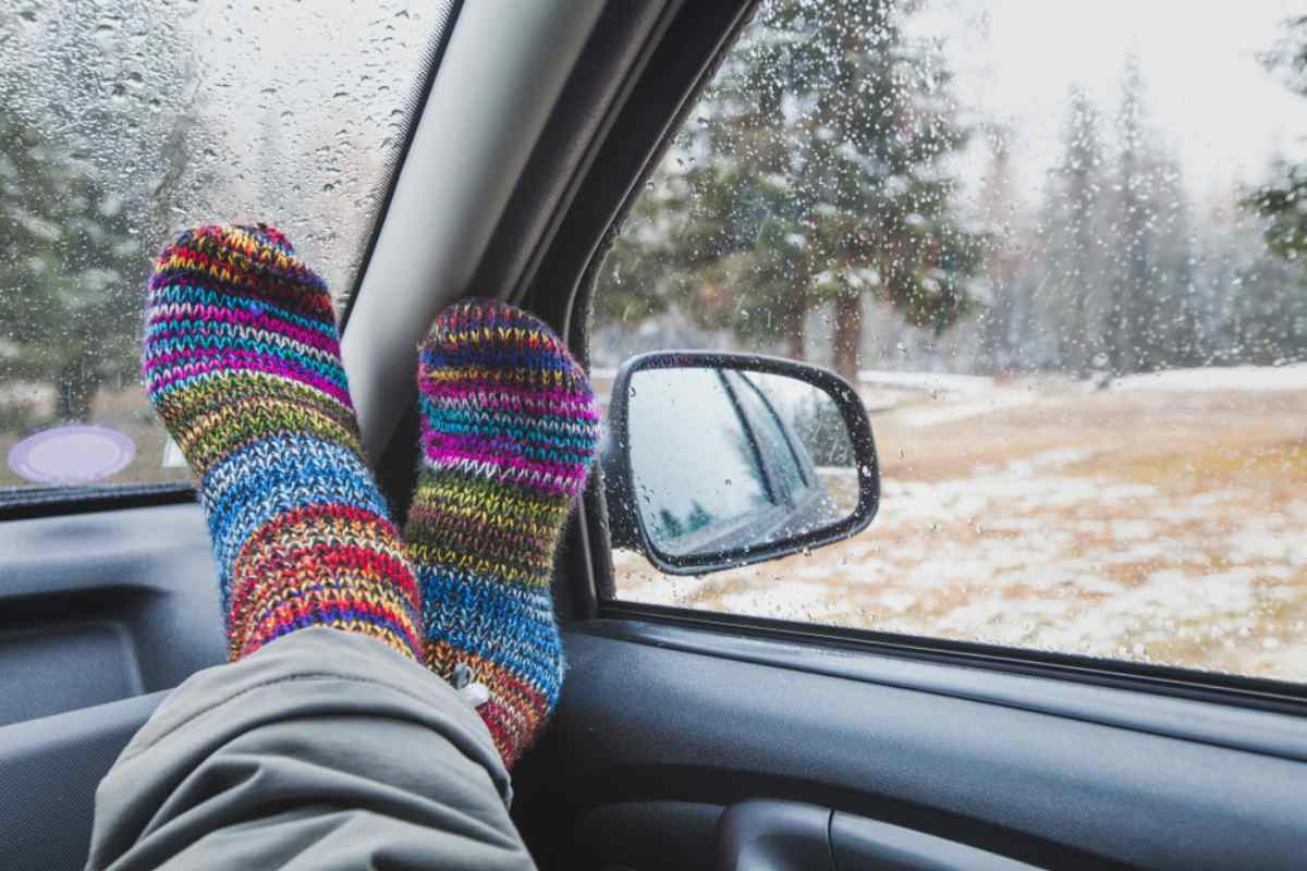 Colorful socks lean against the corner of a car's interior during a rainy day.
