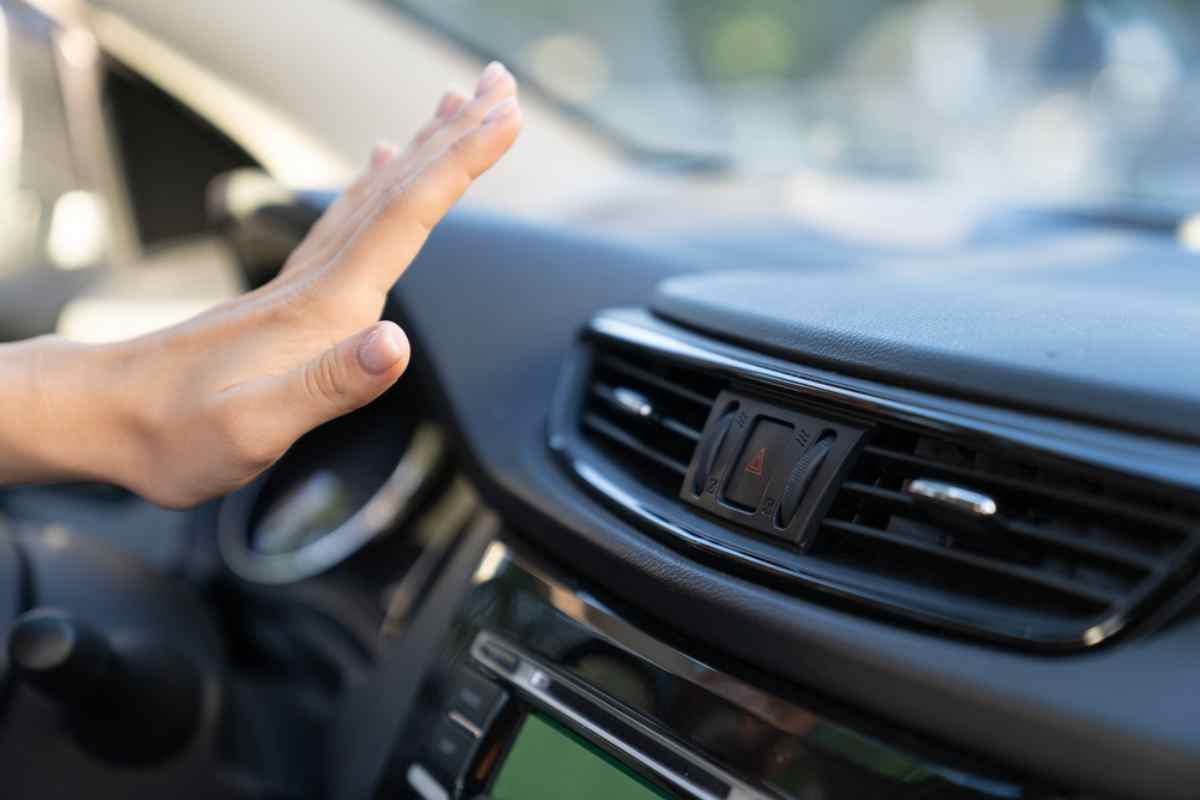Close-up of an open hand in front of a car heater to check whether or not hot air is coming out of it.