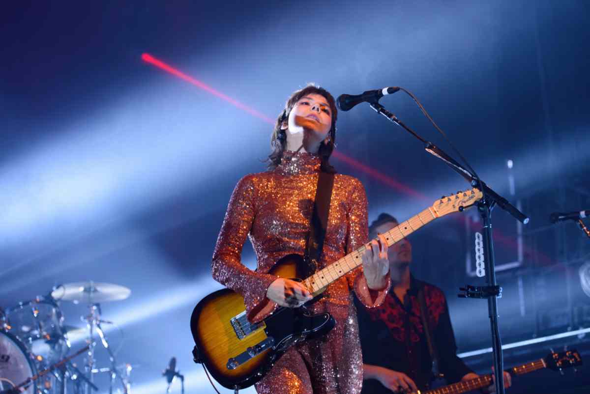 Female artist in a sparkling outfit performing live on stage with an electric guitar and dramatic lighting Icelandic artists