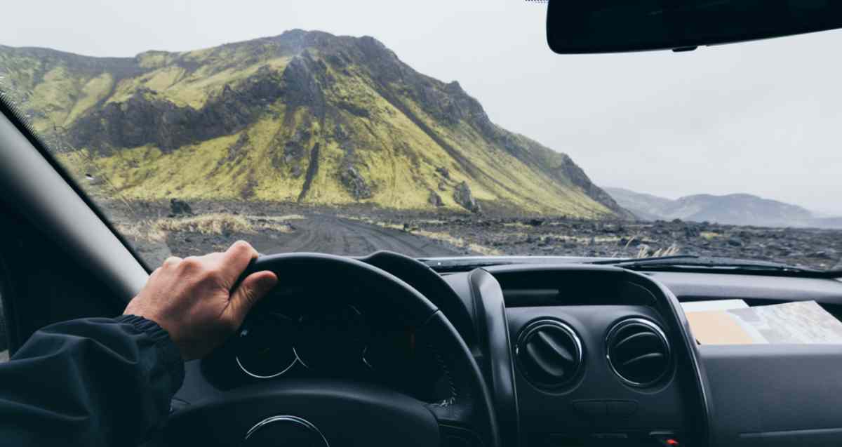 Point of view from inside a car driving toward green volcanic mountains in Iceland Tips to follow on the road