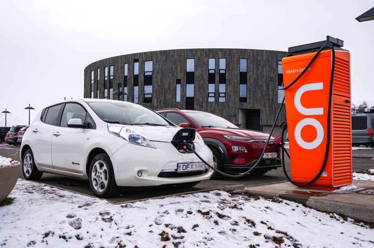 White electric car charging at an orange ON Power station in snowy Iceland.