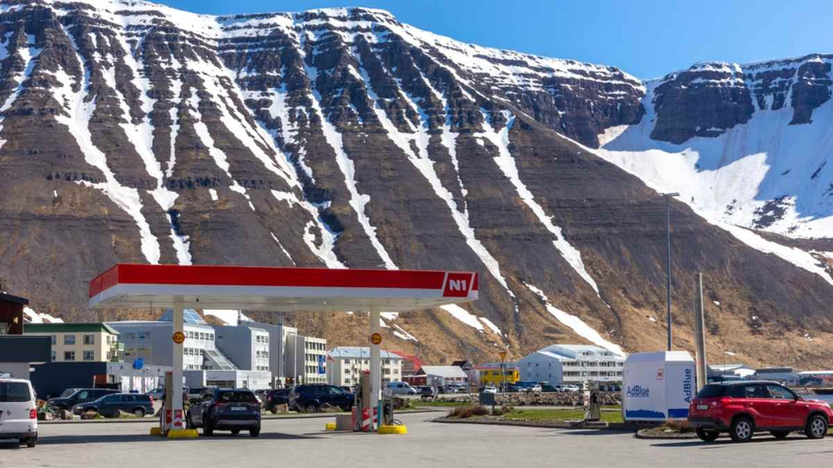 Cars refueling at an N1 gas station with snowy fjord mountains in the background.