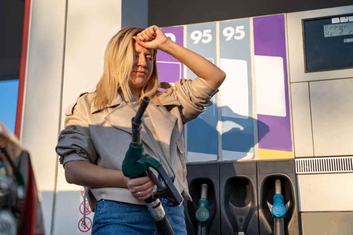Frustrated woman holding a fuel nozzle at an Icelandic gas station.