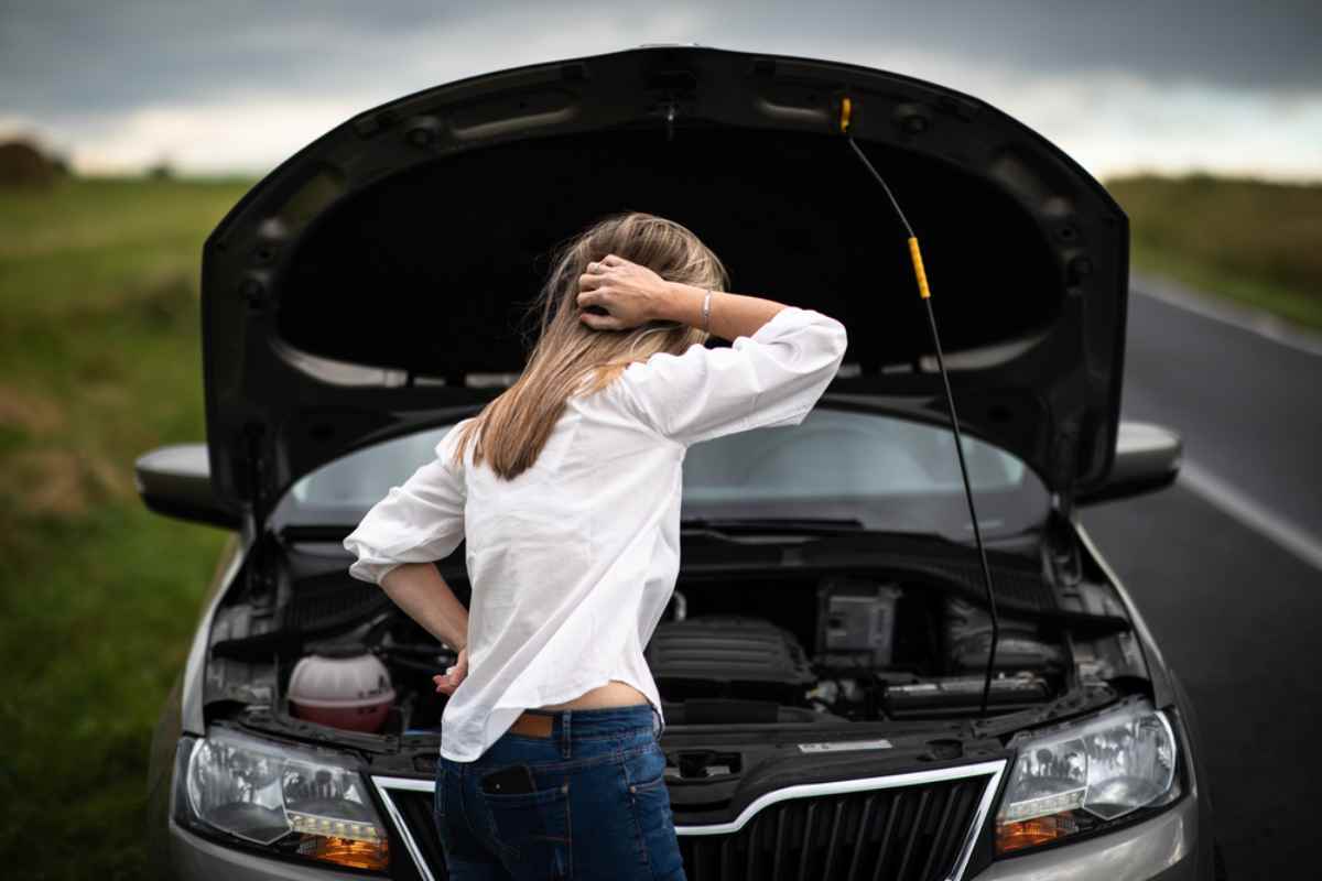 Woman standing by her car with the hood open on an Icelandic road.