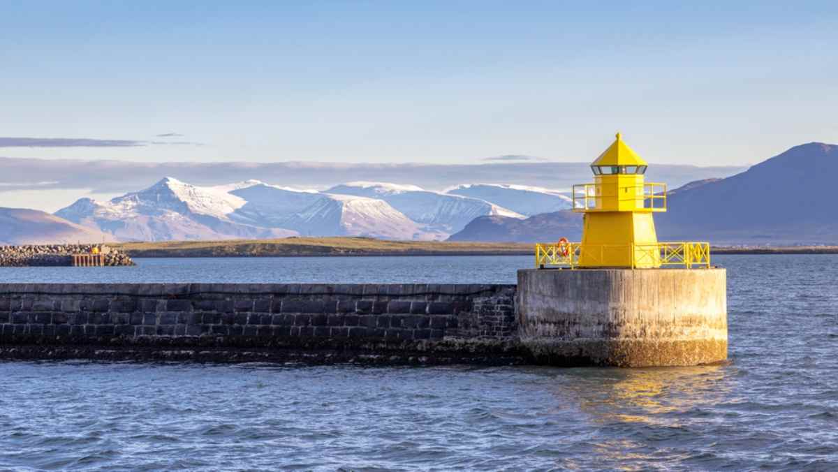 Reykjavik harbor Bright yellow lighthouse at Reykjavík Harbor with snow-capped Esja in the background.