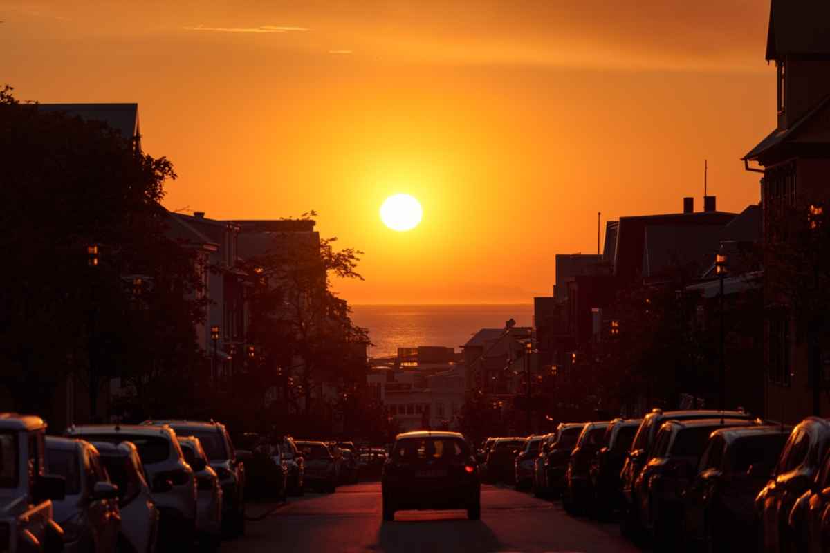 Reykjavik at sunset Reykjavík street at sunset with the sun over the ocean and cars parked along both sides.