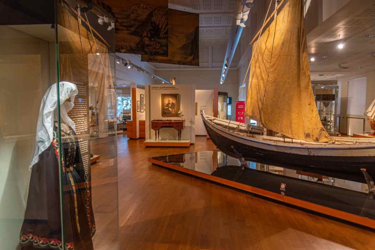 Reykjavik museum gallery featuring a traditional Icelandic boat exhibit, historic artifacts, and warm indoor lighting.