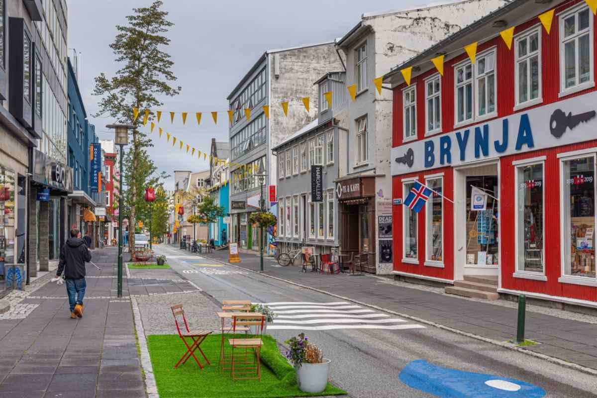 Laugavegur shopping street in Reykjavik, with colorful storefronts, Icelandic flags, and pedestrian-friendly city vibes.